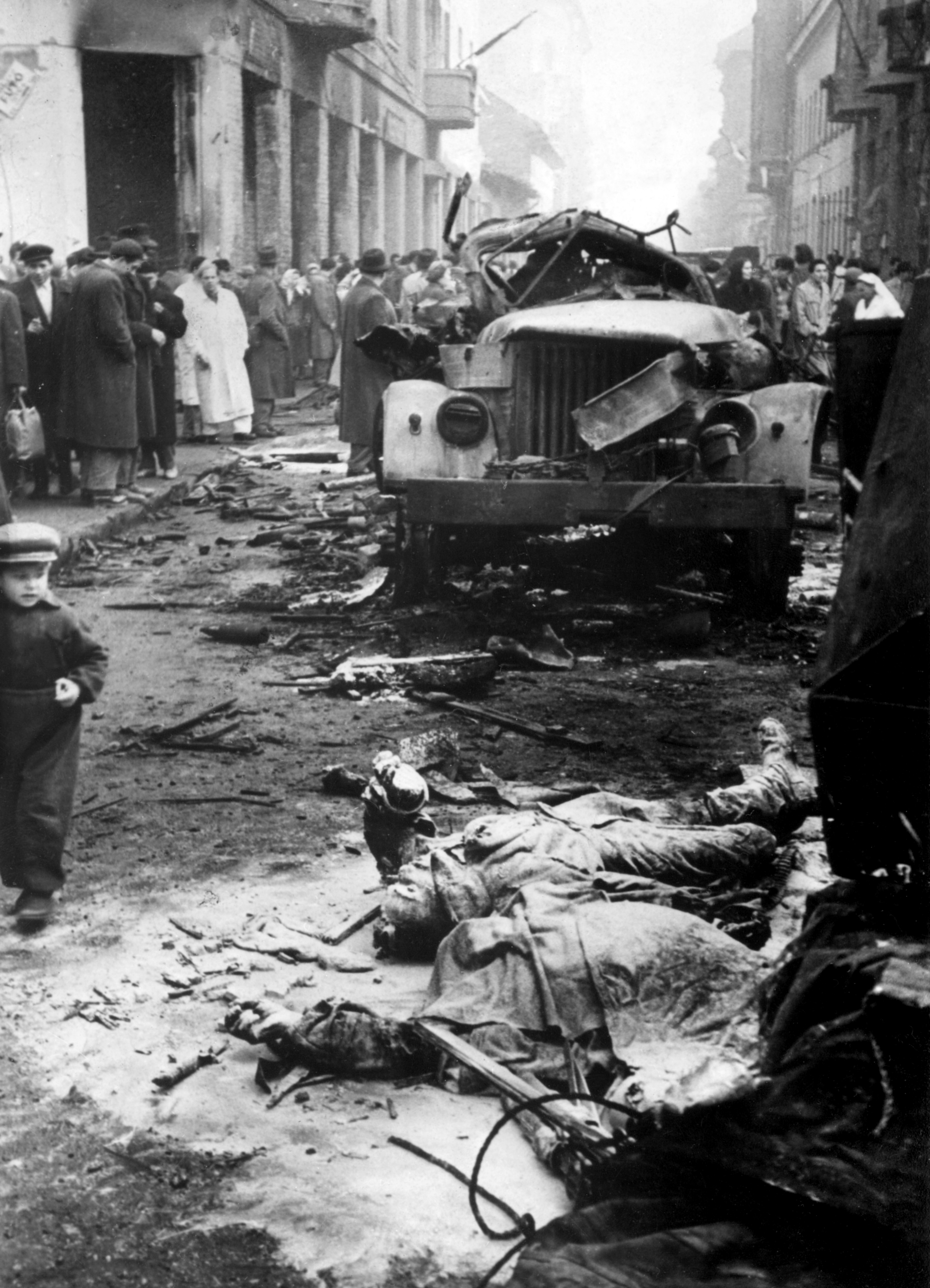 Blick in eine Straße in der ausgebrannte Lastwagen und nur flüchtig zugedeckte Leichen, Budapest 1956, picture-alliance/ dpa